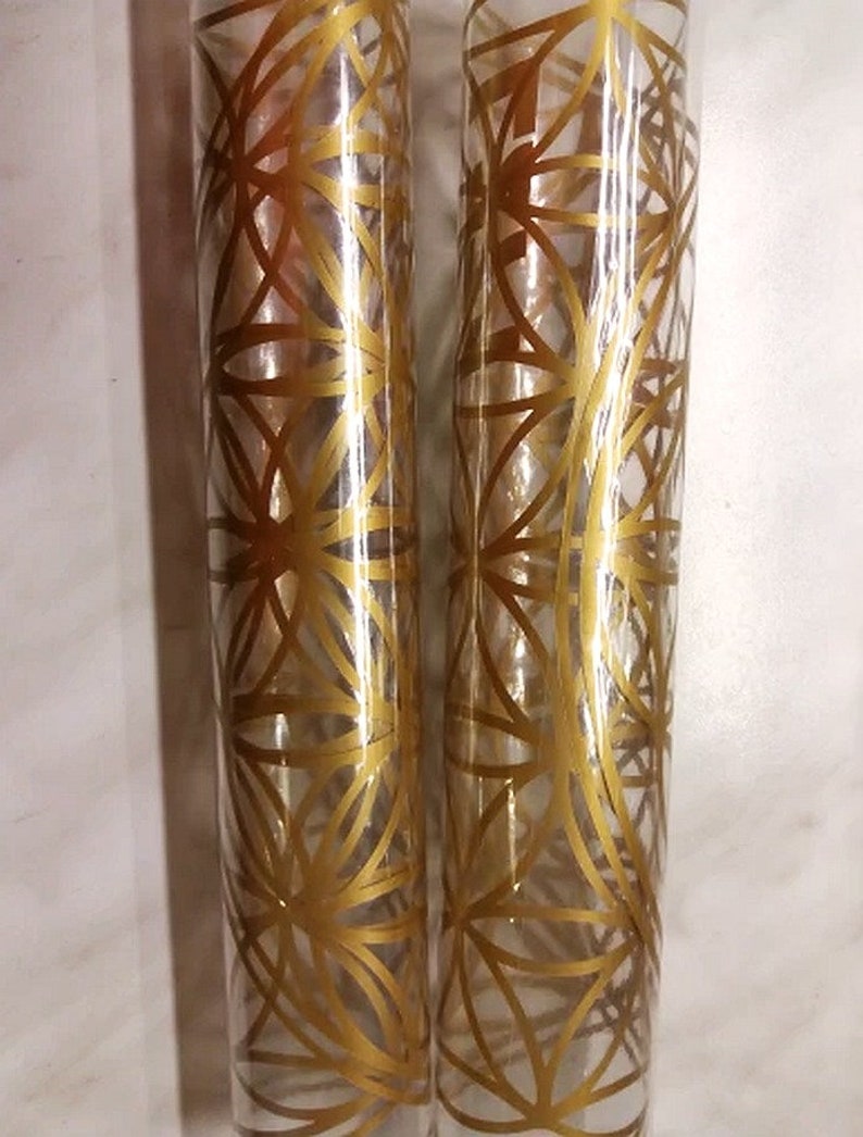 May include: Two clear glass tubes with a gold geometric pattern design.