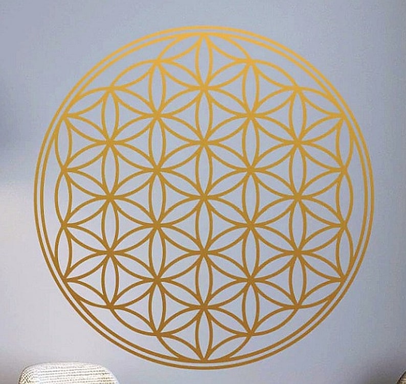 May include: A gold geometric pattern, known as the Flower of Life, is displayed on a light blue background. The pattern is a circle with multiple overlapping circles creating a complex design.