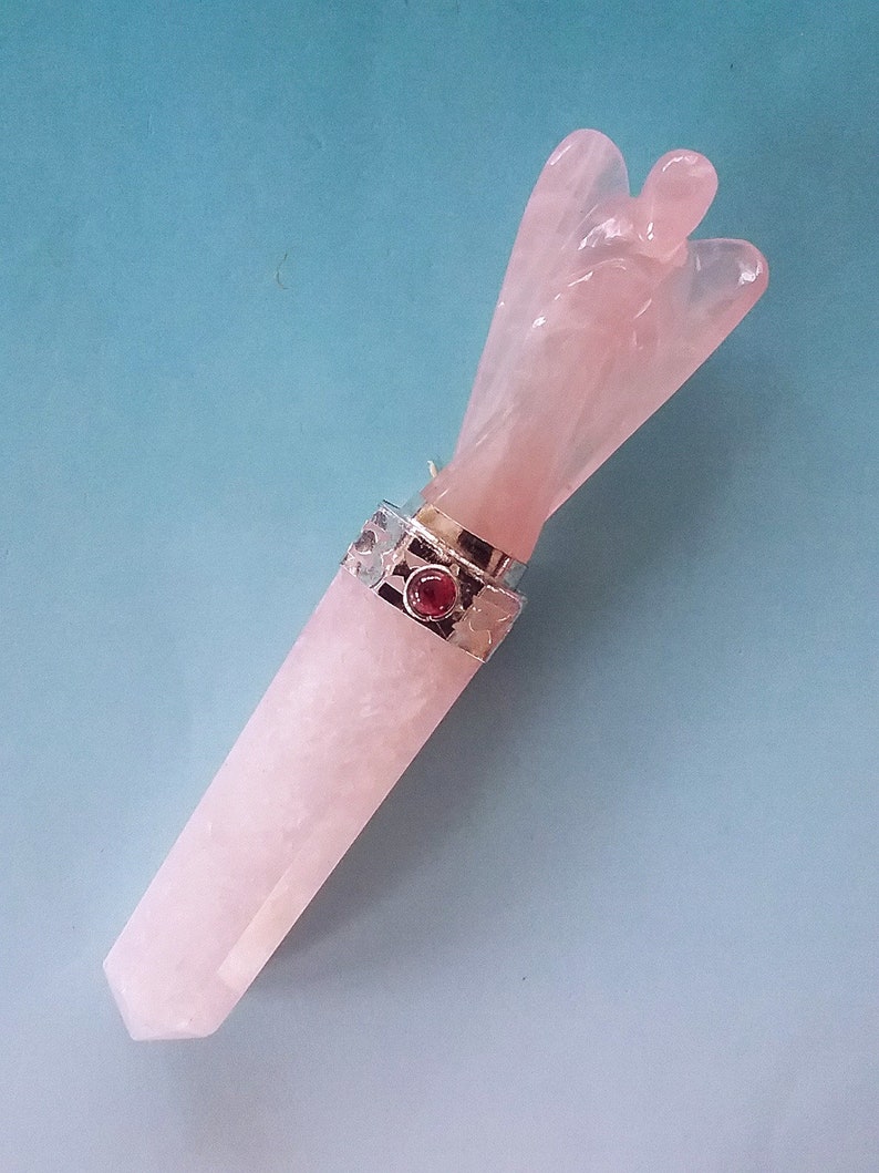 May include: A pink rose quartz angel wing wand with a silver setting and a red gemstone accent.