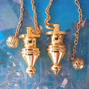 Può includere: Due pendoli in metallo color oro con catene e sfere decorative alla fine di ogni catena. I pendoli sono su uno sfondo blu e bianco.