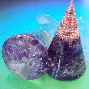 May include: Two amethyst crystal healing orgone pyramids, one is a cone shape with copper wire wrapped around it, the other is a flat disc shape.