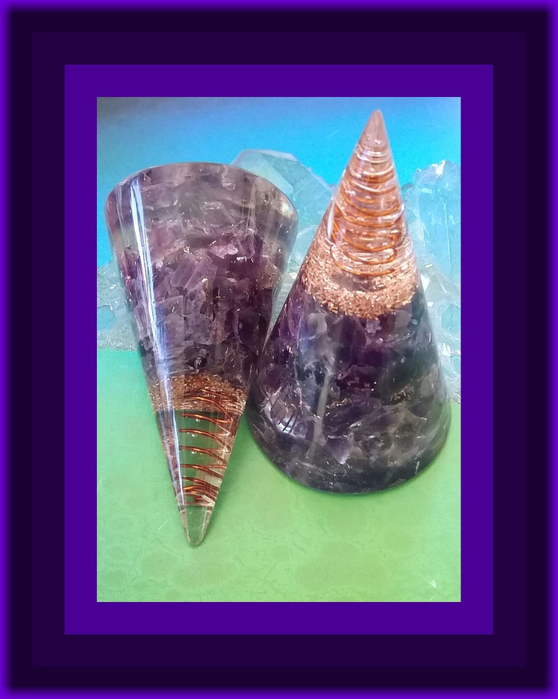 May include: Two amethyst crystal orgonite cones with copper wire spirals. The cones are clear and have a purple hue. The copper wire spirals are visible through the clear crystal.