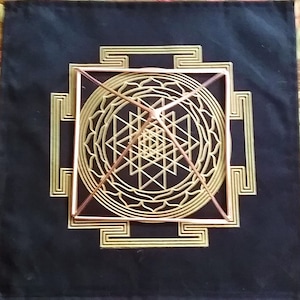 K&ouml;nnte beinhalten: Eine Pyramide aus Kupferdraht liegt auf einem schwarzen Stoffhintergrund mit einem goldenen geometrischen Muster. Die Pyramide ist in einem quadratischen Rahmen zentriert und von einem kreisf&ouml;rmigen Muster umgeben.