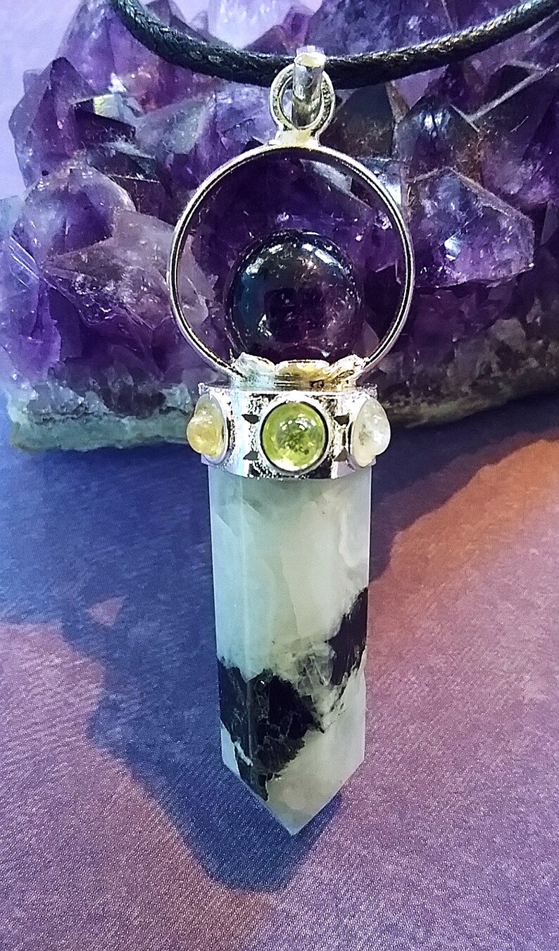May include: A silver pendant with a clear crystal point, surrounded by a silver ring with a purple amethyst sphere inside. The pendant is accented with three smaller stones: two yellow and one green.