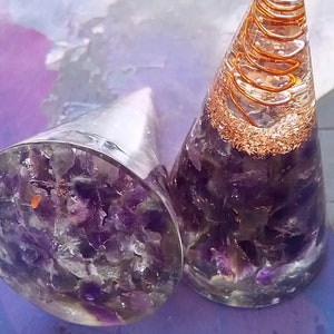 May include: Two amethyst crystal point orgonite pyramids with copper wire spirals. The pyramids are clear and filled with amethyst crystals. The copper wire spirals are visible through the clear resin.