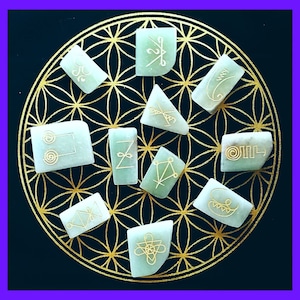 May include: A set of ten green stones with gold symbols etched on them. The stones are arranged in a circle on a black background with a gold flower of life pattern.