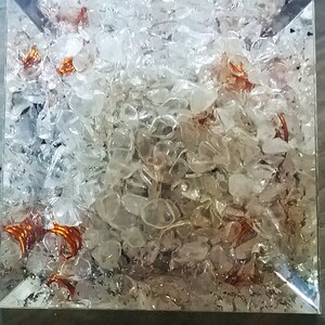 May include: A clear glass cube filled with small, clear quartz crystals and copper wire coils. The crystals are tightly packed together, and the copper wire coils are visible throughout the cube.