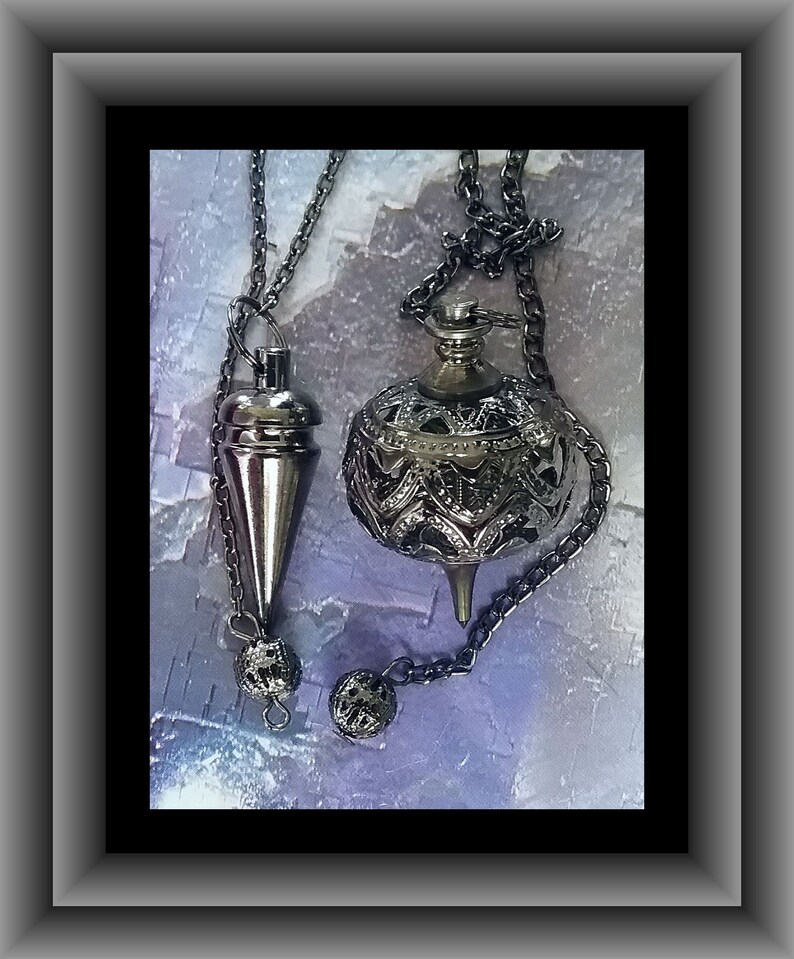 May include: Two silver-toned pendulums hanging from chains. One is a cone shape, the other is a decorative sphere with intricate cut-out designs. Both have small, decorative ball-shaped weights at the bottom. The background is a textured, light blue and purple.