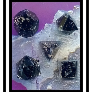 May include: Five black geometric crystal shapes on a purple and white background. The crystals are in various shapes, including a pyramid, a cube, and a dodecahedron.