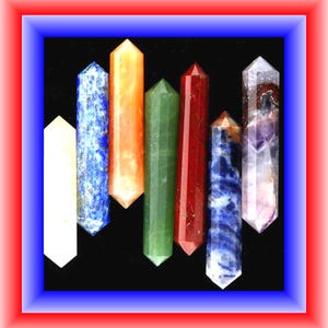 May include: A collection of seven double-terminated crystal wands arranged vertically. The stones include a white quartz, blue lapis lazuli, orange calcite, green aventurine, red jasper, blue sodalite, and a purple amethyst point.