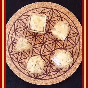 May include: Five clear glass geometric shapes filled with white crystals on a brown cork coaster with a flower of life design.