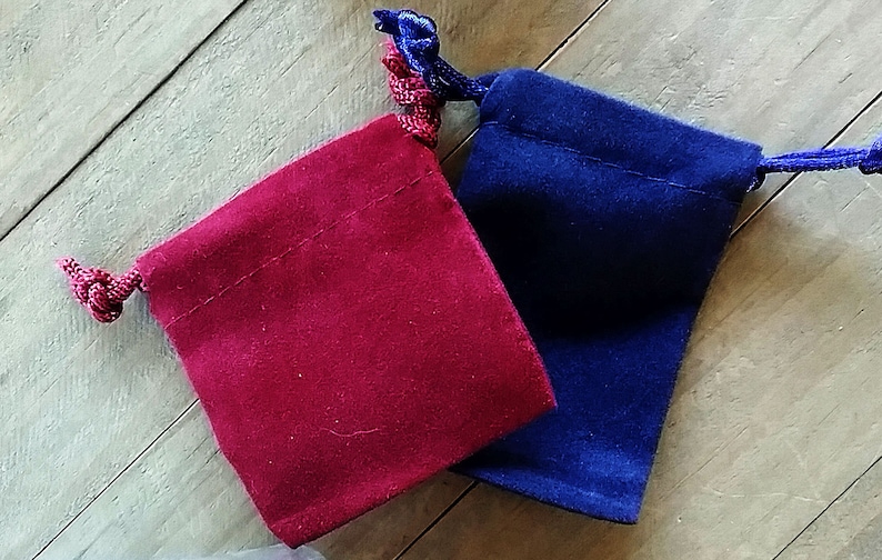 May include: Two small velvet drawstring bags, one red and one blue, with matching cords.