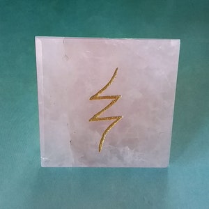 May include: A pink rose quartz pyramid with a gold "life force" symbol etched on the front.