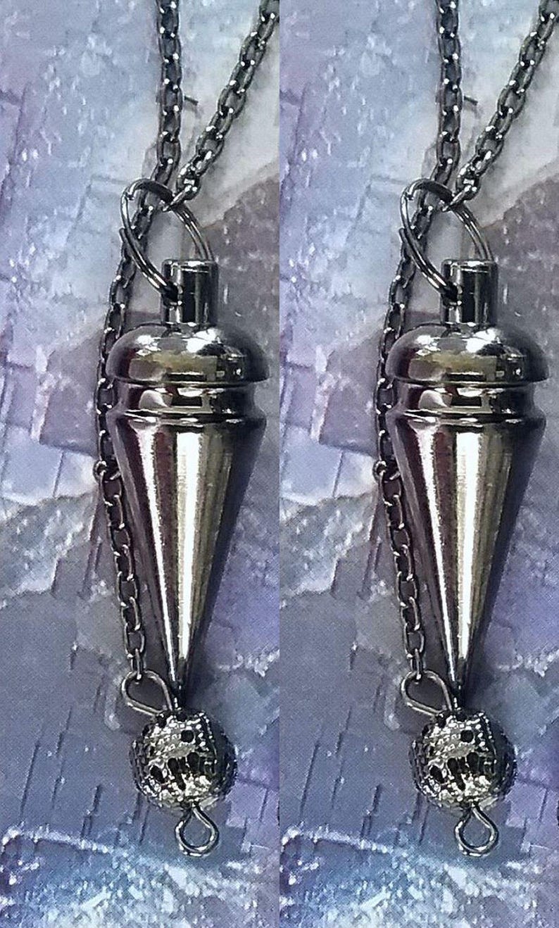 May include: A pair of silver-toned pendulums, each suspended from a chain. The pendulums have a conical shape with a rounded top and a decorative, textured sphere at the bottom. The background has a soft, blurred effect.