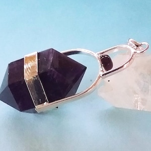 May include: A silver pendant with a dark purple amethyst crystal point and a black bead. The crystal is set in a silver frame with a silver loop for attaching a chain.