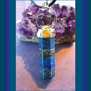 Puede incluir: Un colgante de piedra azul y verde con un engaste plateado y una piedra redonda de amatista en el centro. El colgante est&aacute; rodeado de piedras m&aacute;s peque&ntilde;as de varios colores, incluyendo naranja, rojo y blanco.