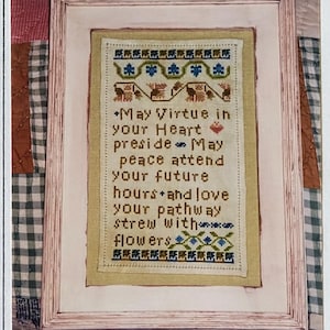 May include: A framed cross-stitch sampler titled "Virtue Sampler" by Tanya Marie Anderson. The sampler features a verse about virtue, peace, and love, with floral and geometric border designs. The frame is light pink.