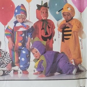 May include: Simplicity Costumes pattern 7475 size A for children. The envelope features five costumes: a dalmatian, a clown, a pumpkin, a purple flower, and a bumblebee. Each costume is shown on a child with colorful balloons in the background.