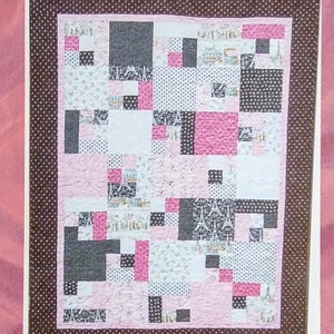 May include: A quilt pattern titled "Fortune Cookie" featuring a patchwork design with pink, white, and black squares. The quilt has a brown polka dot border and includes the text "two chicks quilting patterns".
