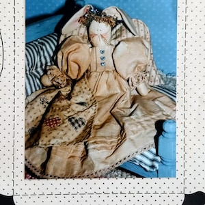 May include: A sewing pattern cover titled Country Stitches featuring a fabric hare doll named Angel-a, a heavenly hare, 12 inches tall. The doll has long ears, a tan dress with blue heart buttons, and a patterned apron with heart motifs.