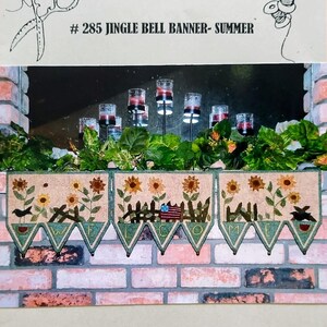 May include: A decorative banner with the text "WELCOME" and a summer theme, featuring sunflowers, birds, and a small American flag. The banner is displayed in front of a brick wall and greenery.