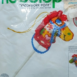 May include: A Jiffy Needlepoint kit for a "Patchwork Pony" Christmas ornament. The package features a colorful, stitched pony head on a stick, with a finished size of 6.5 inches high. The kit includes a 3-D ornament design stitched on both front and back.