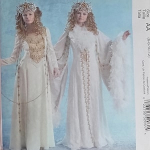 May include: McCall's Costumes pattern M5206. The image shows two women wearing white and cream-colored medieval-style gowns with gold accents and headpieces. The pattern size is AA (6-8-10-12).
