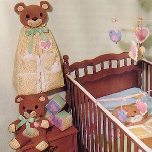 May include: A vintage nursery set featuring a wooden crib, teddy bear-themed accessories, and a dresser. The set includes a diaper stacker, bear toy, mobile, and crib gym. The image also shows the text "Teddy Bear Nursery" and "The Gingham Goose".