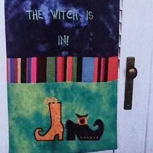 May include: A Halloween-themed embroidery pattern with the text "WELCOME" and "THE WITCH IS IN!" displayed on a decorative banner. The design includes a witch's hat, boots, and other festive elements. The pattern is for a 4x4 hoop and includes 13 embroidery designs.