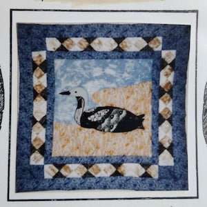 May include: A quilt pattern titled "Arctic Loon" featuring a detailed illustration of a loon in a natural setting. The quilt block measures 12.5 inches, and the wall hanging is 20 inches. The design is by Cari Connolly.
