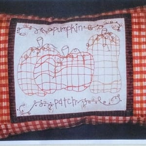 May include: A decorative pillow with a red and white checkered pattern and a central embroidered design. The design features three pumpkins and the words "pumpkin patch" and "family ties". The text "copyright2003" is also visible.