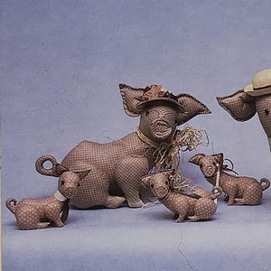 May include: An image featuring a craft pattern titled "Buttermilk Creek" with the text "Hog Wild." The image shows two large pig figures and three smaller pig figures, all wearing hats. The text below indicates the pattern includes instructions for a collar and tie.