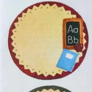 May include: A pattern for Fall Woolies, a quartet of floral wool mug or candle mats, each 6-1/4" in diameter. The mats feature autumn-themed designs, including a chalkboard, flowers, leaves, a sunflower, and a pumpkin. The text "Fall Woolies" is at the top.