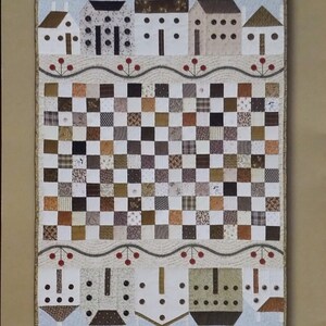 May include: A quilt pattern titled The City Stitcher Quilt Collection #42 Button Town by Janet Miller. The quilt features a central checkerboard of brown, tan, and white fabric squares, bordered by rows of house appliqués with button details.