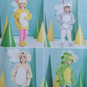 May include: Simplicity pattern R11592 for children's animal costumes. The image shows four different costumes: a yellow cat, a gray bunny, a tan dog, and a green dragon. Each costume includes a hooded top, and matching pants or leggings.
