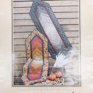May include: Image of a quilt pattern titled "Braid Runner" with two finished table runners. One is a long, rectangular shape, and the other is a shorter, hexagonal shape. The pattern includes the text "Quilt as you go" and the GE-101 product code.