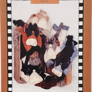 May include: A craft pattern for Wheat Bag Ponies. The image shows several plush pony-shaped wheat bags in various colors, including brown, black, and white. The text reads "Warm Up With" and "Just Heat wheatbag in microwave and cuddle up."