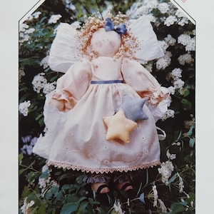 May include: A handmade 15-inch Country Angel doll with a peach-colored dress, wings, and a blue bow. The doll holds two star-shaped ornaments. The image includes text that reads "ADDY 15" Country Angel PATTERN NO. 114" and "FINDERS KEEPERS".