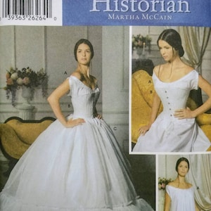 May include: Simplicity sewing pattern featuring a historical fashion design. The pattern includes a white off-the-shoulder gown with a full skirt and corset-style bodice. The cover also shows a simpler white dress. The text reads "The Fashion Historian".