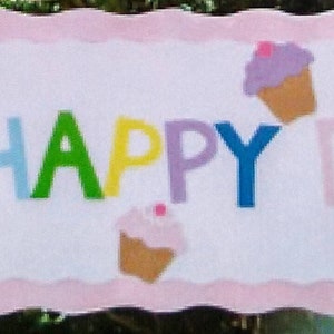 May include: A rectangular banner with a pink scalloped border and the words "OH HAPPY DAY!" in colorful felt letters. Cupcake and party hat felt appliqués decorate the banner, suitable for a birthday celebration.