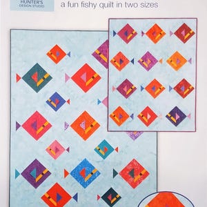 May include: A light blue quilt pattern with colorful fish designs. The quilt features diamond-shaped fish in various colors, including red, orange, purple, and blue. The text "Fin and Dandy" and "a fun fishy quilt in two sizes" is visible.