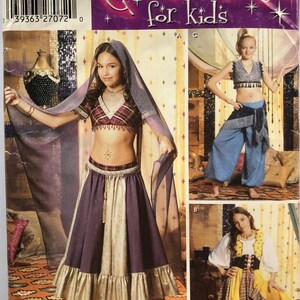 May include: Simplicity costume pattern for kids, featuring three different costume designs. The main image shows a girl in a purple and gold skirt, plaid top, and sheer veil. The pattern includes sizes 7, 8, 10, 12, and 14.