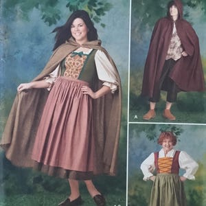 May include: Simplicity pattern 1771A features medieval-style costumes. The image shows a woman wearing a brown cape, a green and brown bodice, and a pink skirt. The pattern includes sizes 8-18/XS-XL.