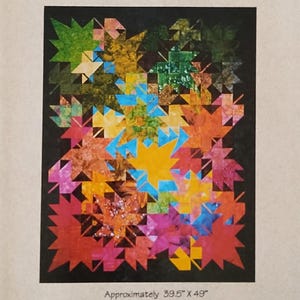 May include: A colorful wall hanging featuring a mosaic of stylized leaves in shades of red, orange, yellow, green, and blue. The wall hanging measures approximately 39.5" x 49" and is titled "New Leaves". The text "Innovations" and "99218" are at the top.
