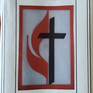 May include: Cutwork wall hanging featuring the United Methodist cross and flame design. The artwork includes a black cross and red flame on a white background, framed in red. The dimensions are 24" x 36". The text "Fashions by Sarah" is at the top.