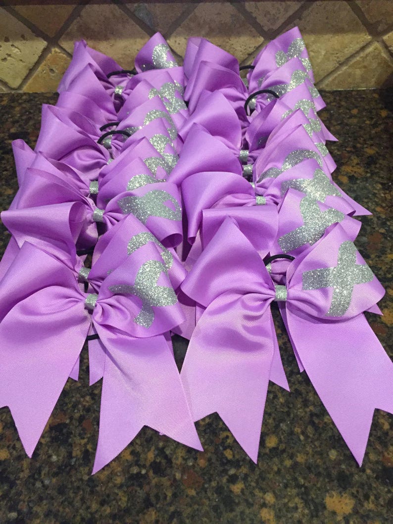 May include: A group of purple hair bows with silver glitter accents. The bows are tied with black elastic hair ties.