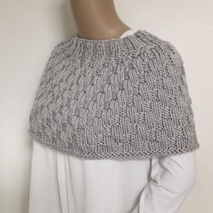 Op de afbeelding: Een grijze gebreide trui met een hoge hals en een textuurpatroon.