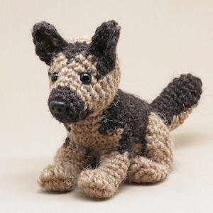 K&ouml;nnte beinhalten: Ein geh&auml;keltes Stofftier in Form eines Hundes mit braunem und braunem Fell. Der Hund sitzt mit den Beinen unter dem K&ouml;rper und dem Schwanz hinter sich eingerollt.