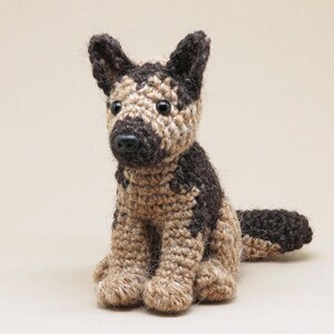 K&ouml;nnte beinhalten: Ein geh&auml;keltes Spielzeug eines Deutschen Sch&auml;ferhund-Welpen mit braunem und braunem Fell. Das Spielzeug hat schwarze Augen und eine schwarze Nase.