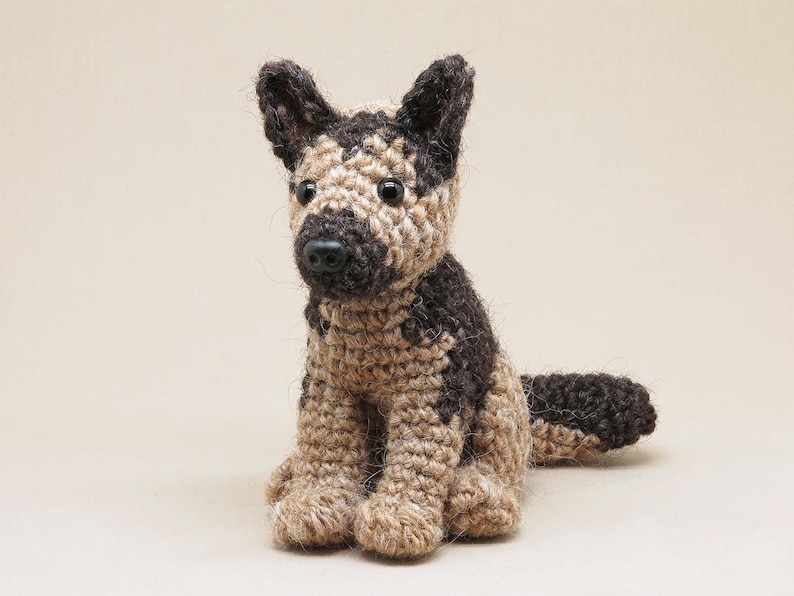 K&ouml;nnte beinhalten: Ein geh&auml;keltes Spielzeug eines Deutschen Sch&auml;ferhund-Welpen mit braunem und braunem Fell. Das Spielzeug hat schwarze Augen und eine schwarze Nase.